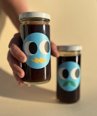 a person holding a jar of honey with a smiley face on it